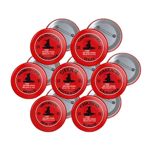 May include: A collection of red round buttons with white lettering and black graphics. Each button features a different city name and the text "j-hope ON THE STAGE".