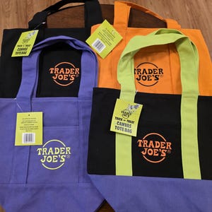 May include: Four Trader Joe's canvas tote bags in black, orange, purple, and black with a purple base. Each bag has the Trader Joe's logo and a tag that says "Trick or Treat Canvas Tote Bag".