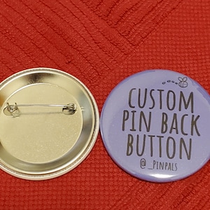 May include: A purple button with the text "CUSTOM PIN BACK BUTTON @ _PINPALS" and a small bee graphic. The back of the button is silver with a pin.