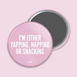 May include: Pink round button with the text "I'm either yapping, napping or snacking" in white.