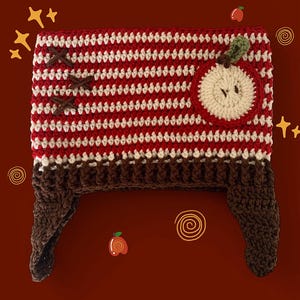 May include: A handmade crochet hat in red and white stripes, with a brown brim and ear flaps. The hat features a crochet apple applique with a green leaf. Brown cross-stitch details decorate the side. The hat is a unique, cozy accessory.