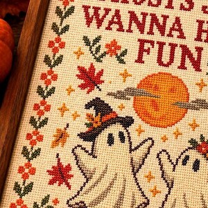 Peut inclure: Une broderie au point de croix dans un cadre en bois repr&eacute;sentant deux fant&ocirc;mes blancs, dont l'un porte un chapeau de sorci&egrave;re, entour&eacute;s de citrouilles orange, de feuilles d'&eacute;rable rouges et d'une pleine lune. Le texte indique GHOSTS WANNA HAVE FUN.