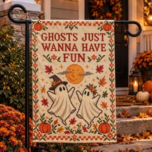 Peut inclure: Un drapeau de jardin rectangulaire avec un motif style point de croix sur fond cr&egrave;me. Le texte indique GHOSTS JUST WANNA HAVE FUN. Le design comprend deux fant&ocirc;mes blancs, une lune jaune, des citrouilles orange et des feuilles d'automne.