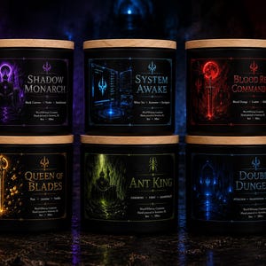 May include: Six black cylindrical candles with light wood lids, each featuring a unique graphic label. The labels are titled Shadow Monarch, System Awake, Blood Red Commander, Queen of Blades, Ant King, and Double Dungeon, with printed scent notes.