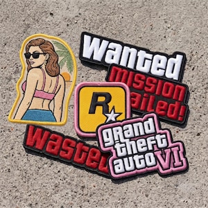 May include: A collection of embroidered patches featuring a woman in sunglasses, a yellow square with a black R and white star, and text patches reading Wanted, Mission Failed, Wasted, and Grand Theft Auto VI in various colors and fonts.