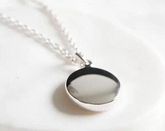 May include: A silver chain necklace with a round, smooth pendant.