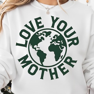 以下が含まれることがあります： 「LOVE YOUR MOTHER」の文字がダークグリーンでプリントされた白いスウェットシャツ。地球のダークグリーンのグラフィックが周りに描かれています。クルーネックのデザインです。