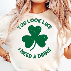 May include: White t-shirt with a green shamrock and the text "You look like I need a drink".