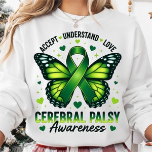 May include: White sweatshirt featuring a green butterfly design with a green ribbon and the words "ACCEPT UNDERSTAND LOVE" and "CEREBRAL PALSY Awareness". The design includes green hearts and stars.
