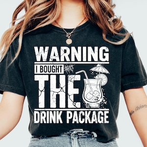 May include: Black t-shirt with a distressed white graphic that reads "WARNING I BOUGHT THE DRINK PACKAGE." The graphic includes a cocktail with a straw, ice cubes, and a small umbrella. The shirt is a casual style.