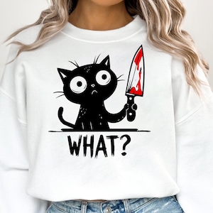 Op de afbeelding: Wit sweatshirt met een zwarte kat die een bloedig mes vasthoudt en de tekst "WHAT?" op de voorkant.