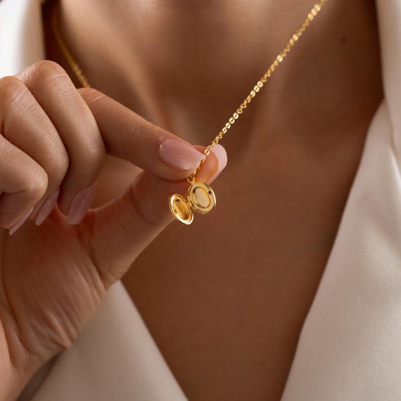 A tiny oval gold locket necklace with 113 favorites — the mini photo locket format is a timeless, genuinely sentimental personalized gift that never gets old.