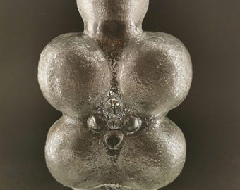 May include: A clear glass vase with a textured surface. The vase has a unique shape, with rounded sections and a narrow neck. The design includes small, circular embellishments. The vase is likely for decorative purposes.