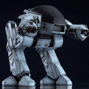 May include: A white and black articulated robot with a black head and a gun on each arm. The robot is standing on a black surface.