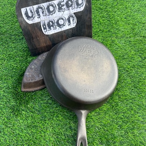 May include: A cast iron skillet with a black handle. The skillet is marked "Wagner Ware Sidney -O- 1055E".