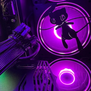May include: A close-up of a computer case with purple LED lights illuminating the interior. The case features a black and silver design with a cutout of a Pokemon character, possibly a  Eevee, on one of the fans.