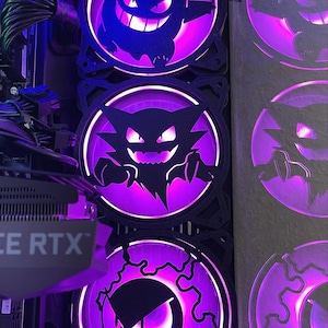 May include: Computer case fans with purple LED lighting and black cartoon character silhouettes. The fans are arranged vertically, with the characters' faces lit by the purple light.