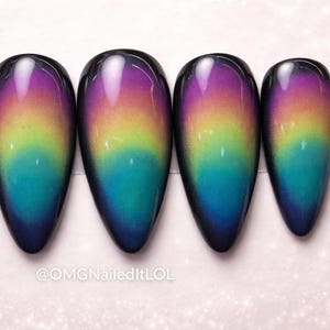 May include: Five almond-shaped artificial nails with a color-changing effect. The nails transition from a deep purple at the cuticle to a vibrant rainbow gradient of yellow, green, and blue at the tips. The text "@OMGNailedItLOL" is at the bottom.