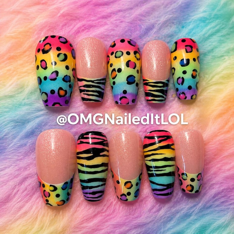 Op de afbeelding: Een set van tien kunstnagels met diverse ontwerpen. Sommige nagels hebben een regenboog luipaardprint, andere hebben een roze glitterbasis met zebra strepen of luipaardprint tips. De tekst "@OMGNailedItLOL" is zichtbaar.