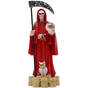 May include: A red-robed figurine of a skeletal figure holding a scythe and a crystal ball. An owl sits atop a stack of gold coins. The figure has a hood and is standing upright.