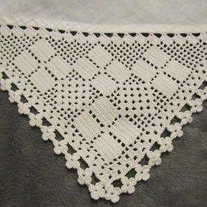 Puede incluir: Borde de encaje blanco tejido a crochet con un patrón geométrico. El encaje es delicado e intrincado, con un borde festoneado.