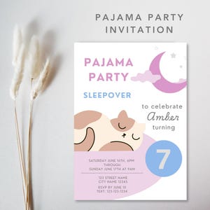 May include: A pink and blue invitation for a pajama party sleepover to celebrate Amber turning 7. The invitation features a cartoon cat sleeping on a pink cloud with a crescent moon and stars in the background. The text on the invitation includes the date and time of the party, the address, and RSVP information.