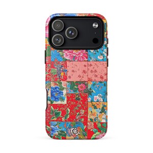 May include: A patterned phone case with a patchwork design. The case features floral patterns in red, blue, pink, and yellow. The phone case has a black camera module.