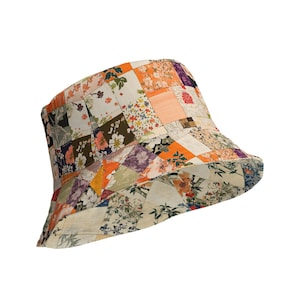 May include: A patchwork bucket hat featuring a variety of floral and geometric patterns in shades of orange, white, green, and purple. The hat has a wide brim and a rounded crown, perfect for sun protection.