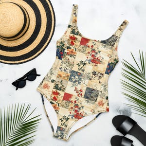 Può includere: Un costume da bagno intero con un design patchwork di varie illustrazioni floreali e botaniche nei toni del rosso, blu e crema. Il capo presenta uno scollo rotondo e spalline larghe, con un motivo a griglia che si ripete.