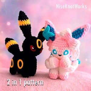 Könnte beinhalten: Zwei gehäkelte Plüschfiguren: ein schwarzes Umbreon mit gelben Akzenten und ein rosa Sylveon mit blauen Akzenten. Das Umbreon hat gelb gefärbte Ohren und einen Schwanz mit gelben Kreisen. Das Sylveon hat rosa und weißes Fell mit blauen Akzenten. Der Text lautet "2 in 1 pattern".