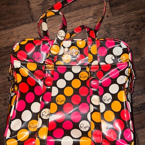 May include: A black, pink, yellow, and white polka dot tote bag with the word "Roxy" repeated on the bag.
