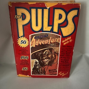 May include: Vintage pulp magazine titled "The PULPS" with a red cover and yellow lettering. The cover features a central illustration of a man holding a gun, with the text "MANCHU TERROR". Additional text includes "Mammoth Adventure" and author names.