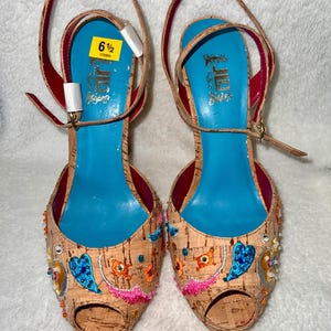 Puede incluir: Tacones de cuña de corcho con puntera abierta y bordado colorido. Los tacones están decorados con cuentas, lentejuelas y flores de tela. La etiqueta de talla dice "6 1/2".