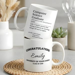 May include: Two white ceramic mugs stacked on a woven coaster. The top mug reads "Computer Science Graduate" with a definition. The bottom mug says "Congratulations Emily, University of Your Choice, Class of 2026."