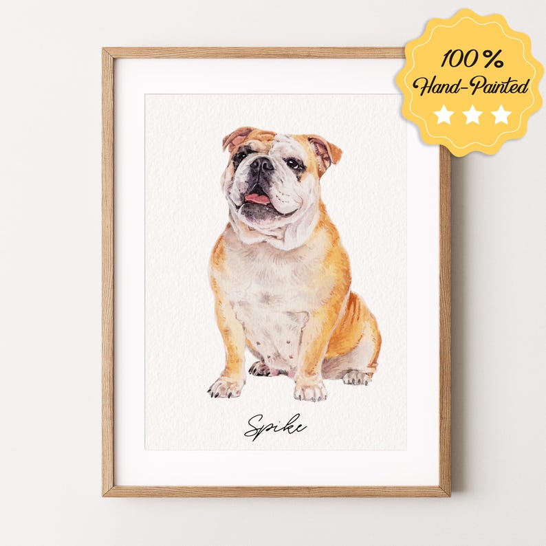 May include: A watercolor painting of a bulldog sitting. The dog is brown and white with a pink nose. The painting is framed in a light wood frame. The dog's name, "Spike", is written in cursive at the bottom of the painting.