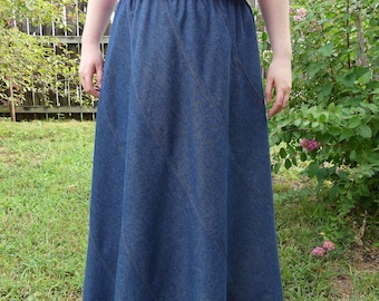 May include: A long denim skirt with a diagonal seam design. The skirt is a dark blue color and has a wide waistband.