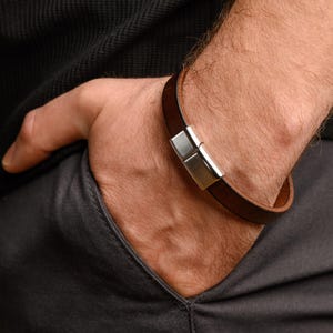 May include: A brown leather bracelet with a silver magnetic clasp.