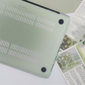 May include: A pale green MacBook Pro case with ventilation slots and black detailing. The case has a translucent finish. The text "MacBook Pro" is printed on the case.