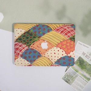 May include: A colorful laptop case featuring a patchwork design with various patterns, including red plaid, blue floral, and yellow stripes. The case has a white Apple logo in the center, and is designed to fit a laptop.