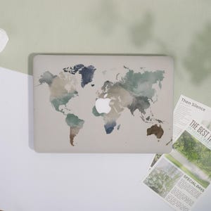 May include: A laptop case featuring a world map design in watercolour shades of blue, green, and brown. The case has a white Apple logo. The design is set against a neutral background.