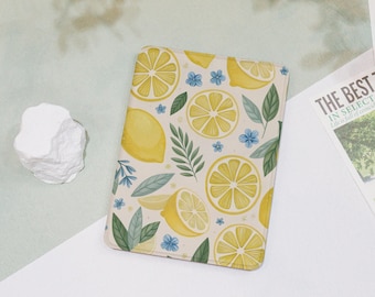 May include: A rectangular notebook with a lemon pattern. The design features yellow lemon slices, whole lemons, green leaves, and small blue flowers on a cream background. The notebook is on a white surface.