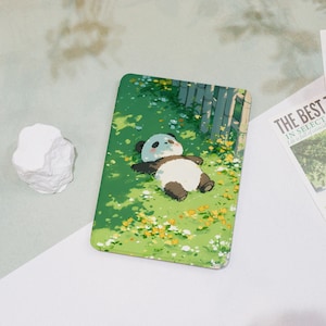 May include: A rectangular phone case featuring a cartoon panda relaxing on a grassy field with yellow flowers. The panda has black and white fur and is lying down. The background includes bamboo and a bright green color.