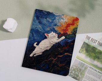 May include: A notebook featuring a white cat leaping across a colorful, textured background of blues, oranges, and reds. The cat is rendered in a 3D style, with its eyes closed and paws outstretched. The notebook is on a white surface.