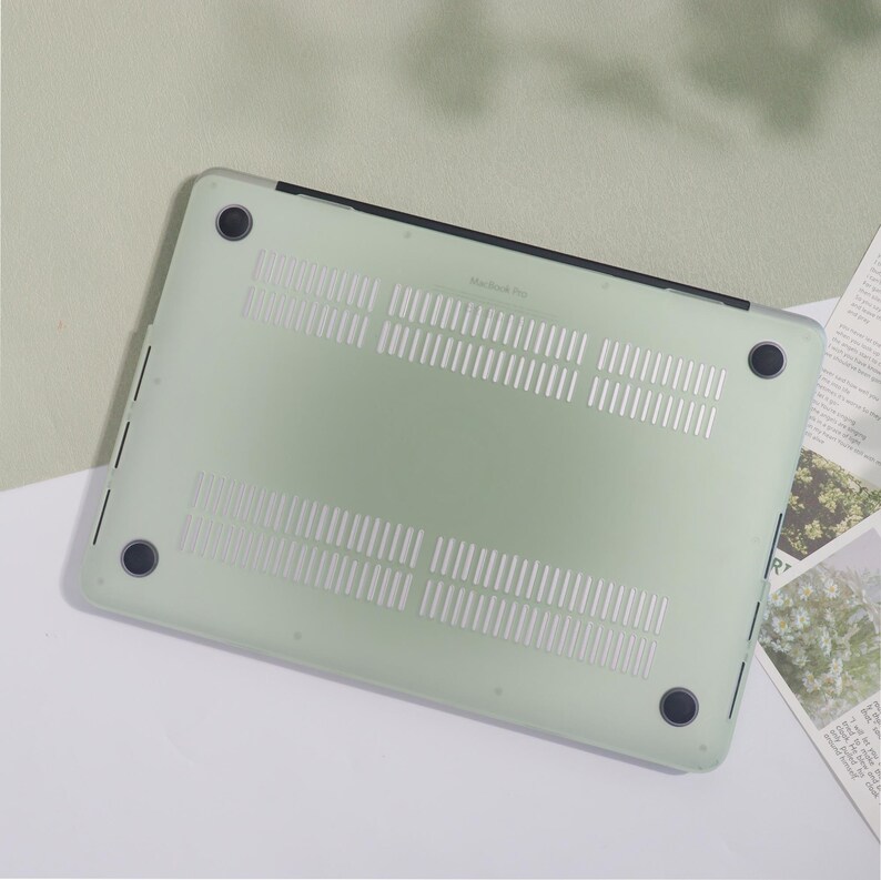May include: A pale green MacBook Pro case with a transparent design. The case features ventilation slots and four black rubber feet. The case is designed to protect the laptop from scratches and other damage.
