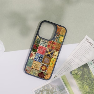 May include: A smartphone case with a dark blue border and a mosaic tile design. The mosaic features various floral, geometric, and sun patterns in shades of red, yellow, blue, and green. The case is lying on a white surface.