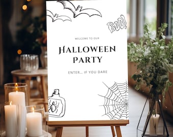 Könnte beinhalten: Ein weißes Halloween-Partyschild auf einer hölzernen Staffelei. Das Schild zeigt schwarze Illustrationen von Fledermäusen, einem Spinnennetz und einer Flasche mit einem Spinnennetz. Der Text auf dem Schild lautet "Welcome to our Halloween Party" und "Enter... if you dare."