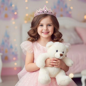 May include: A young girl wearing a pink dress and a pink jeweled crown, holding a white teddy bear. The background features a soft focus with a castle illustration and fairy lights.
