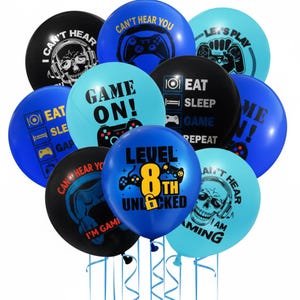 May include: A collection of blue, black, and teal balloons with gaming-themed graphics and text. The balloons feature phrases like "Game On!", "Level 8th Unlocked", and "Eat Sleep Game Repeat". The balloons are tied with blue ribbons.