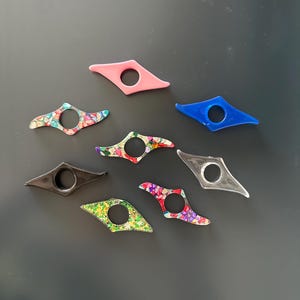 Puede incluir: Una colecci&oacute;n de ocho marcap&aacute;ginas coloridos en varios dise&ntilde;os. Los soportes est&aacute;n hechos de pl&aacute;stico y tienen forma de diamante con un agujero en el centro.