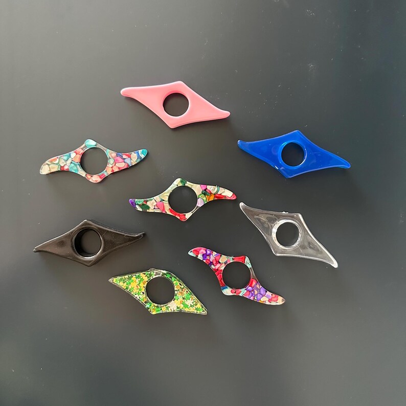 Puede incluir: Una colecci&oacute;n de ocho marcap&aacute;ginas coloridos en varios dise&ntilde;os. Los soportes est&aacute;n hechos de pl&aacute;stico y tienen forma de diamante con un agujero en el centro.